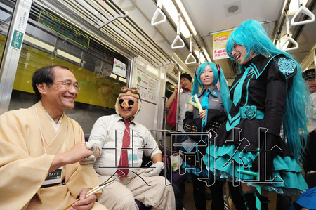 9月2日，京都市交通局开出一趟“cosplay列车”为地铁做宣传。图为京都市长门川大作（左1）与cosplay玩家在车厢内交谈。（共同社）